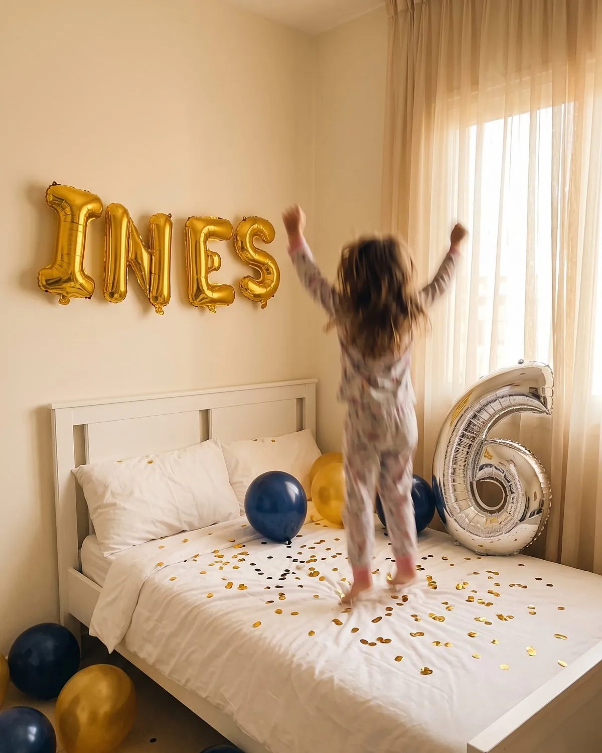 Ballons lettres dorés INES et chiffre 6 argenté au-dessus d'un lit d'enfant