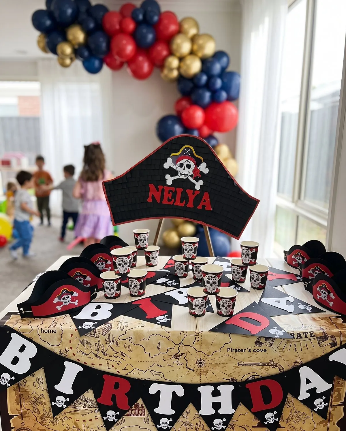 Table d'anniversaire pirate au prénom de Nelya, avec piñata et bannière